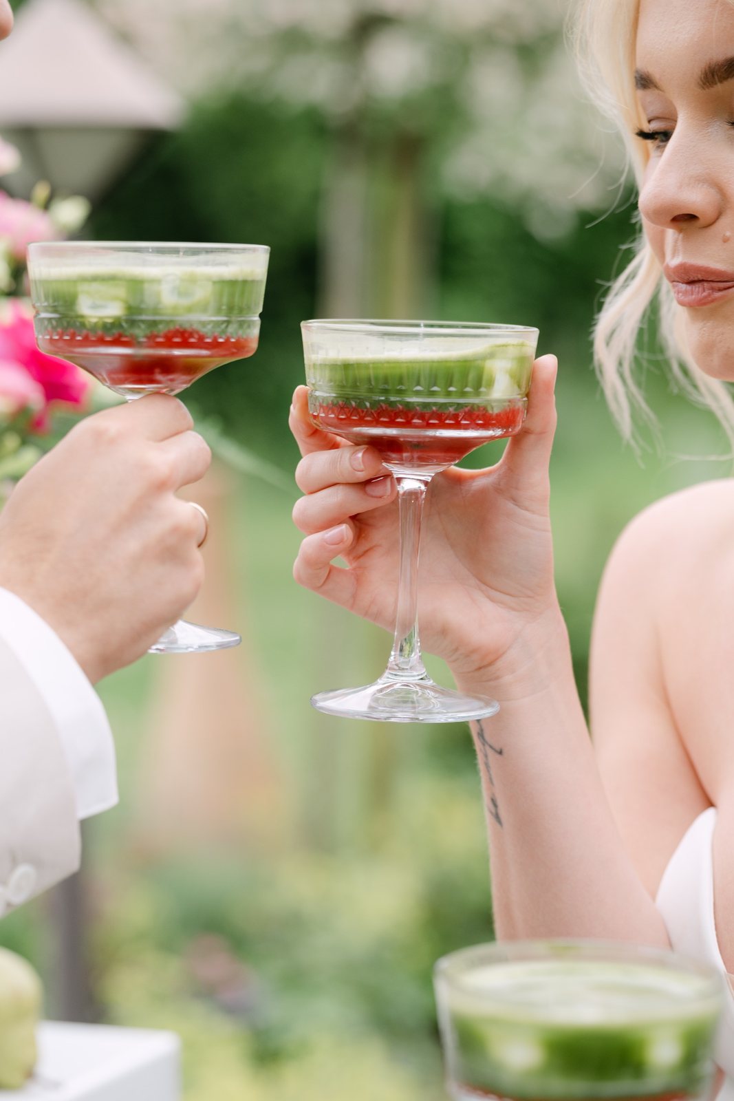 Brautpaar stößt mit grünen Matcha-Cocktails in Kristall-Coupes an