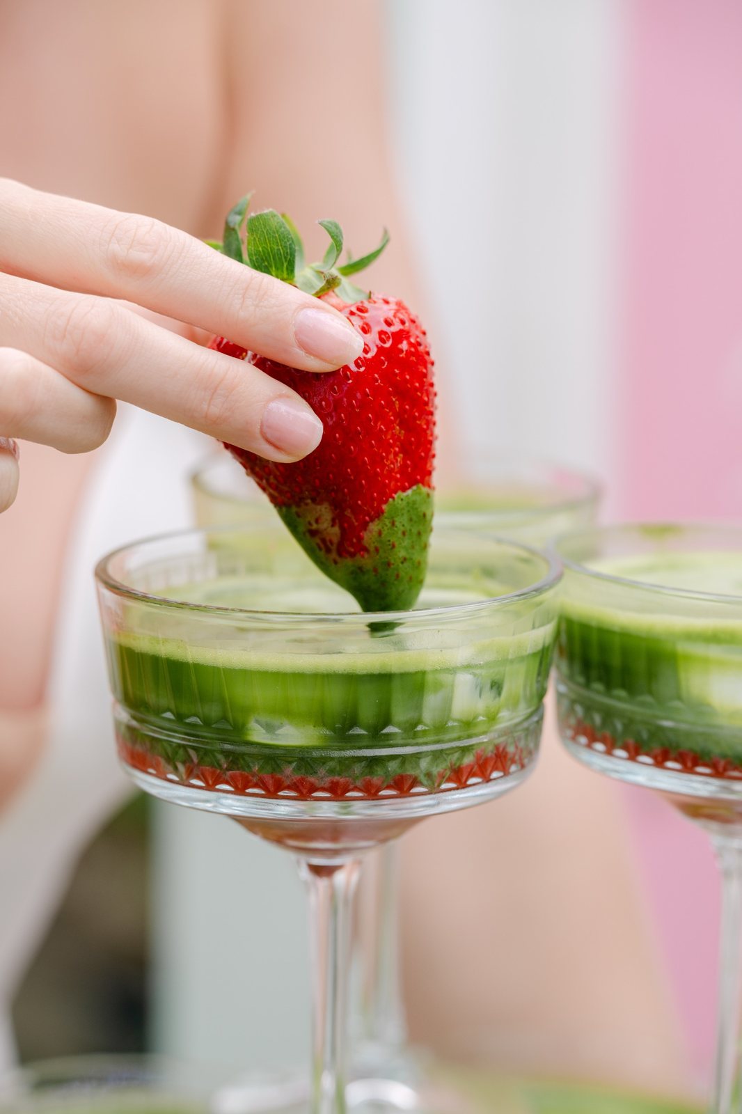 Frische Erdbeere wird in einen grünen Matcha-Cocktail getaucht
