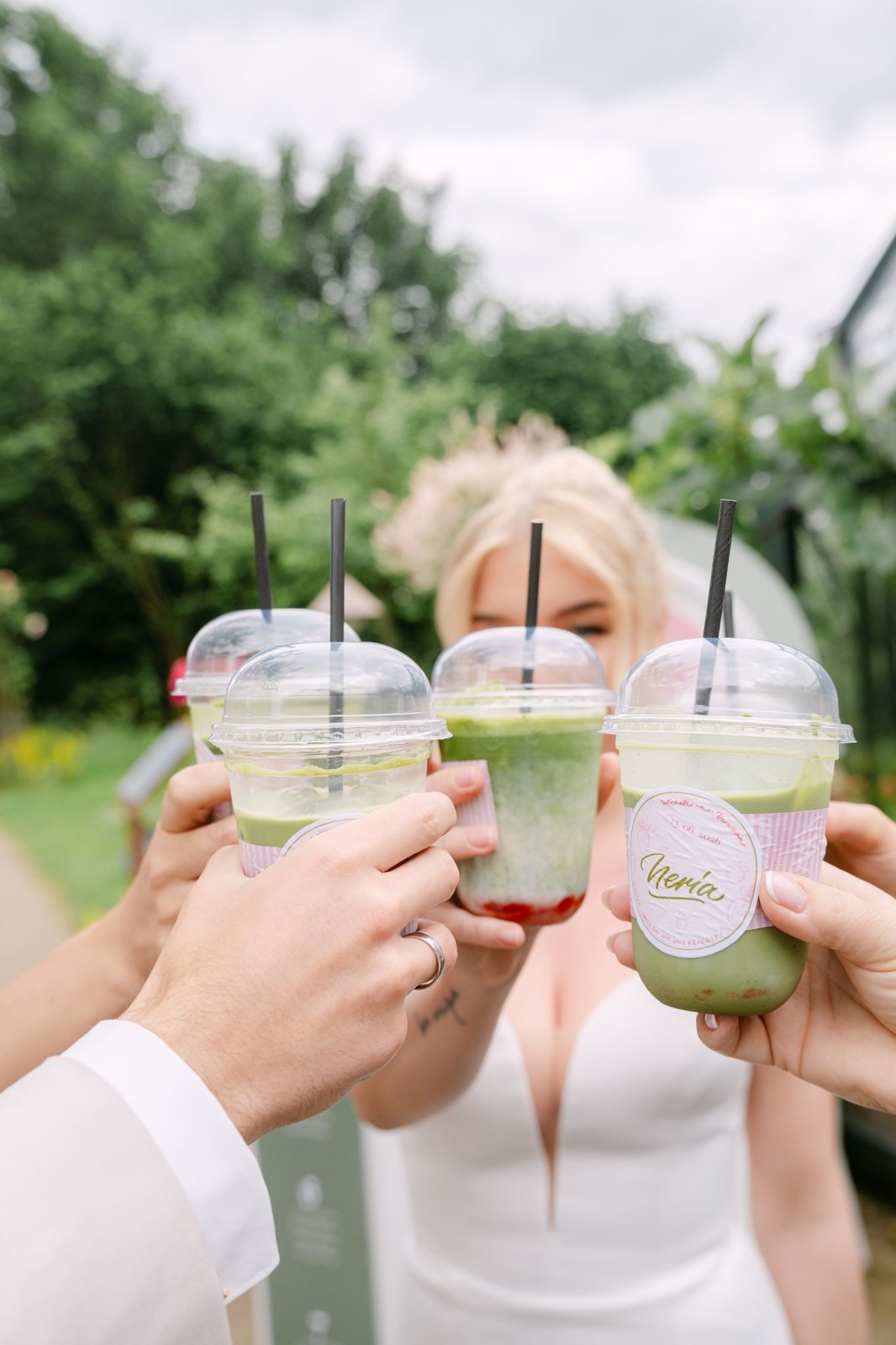 Anstoßen mit eisgekühlten Iced-Matcha-Bechern im Grünen